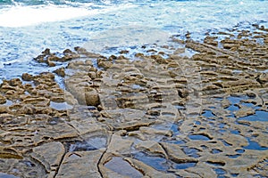 The rock pools in the sandstone shelf on the beach at Sliema, Malta
