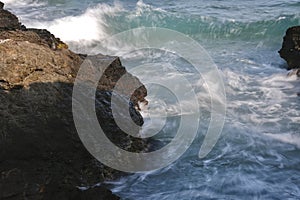 In the rock that protrudes on the coast, the waves collide with it photo