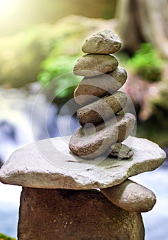 Rock pyramid, rock balancing art. Close-up of a stack of stones in perfect balance in a mountain forest. Sun rays.
