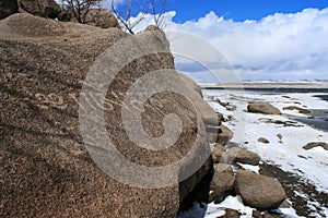 Rock with religious buddhist inscriptions in the snowy steppe of Mongolia on a sunny day