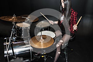 Rock and roll girl playing hard rock music with drums set