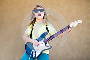 Rock and roll, little kid rock star. Little boy playing guitar outdoor. Music for children.