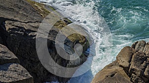 Rock in the sea. The waves breaking on a stony beach.