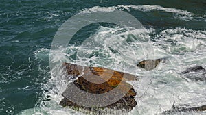 Rock in the sea. The waves breaking on a stony beach.