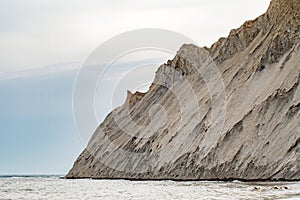 Rock of sedimentary rocks with steep slopes and peaks in sea close-up