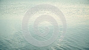 Rock skips across calm water surface leaving ripples and circles