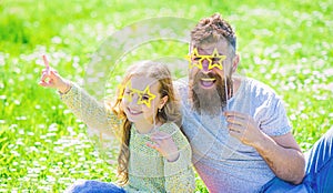 Rock star concept. Dad and daughter sits on grass at grassplot, green background. Family spend leisure outdoors. Child photo