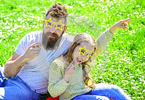 Rock star concept. Family spend leisure outdoors. Father and daughter sits on grass at grassplot, green background