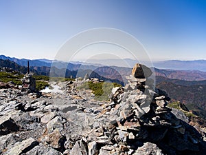 Rock, stone and cairn on hill with the clear blue sky and mountains background