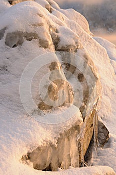 Rock stones covered with ice, snow and icicles on the Yenisei river bank during winter foggy dawn