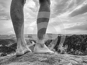 Rock with tired hikers legs without shoes. Naked male legs