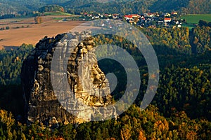 Rock and village. Schrammsteine, beautiful evening view over sandstone cliff into deep misty valley in Saxony Switzerland, foggy