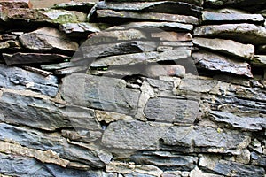 Rock wall made of both stacked and mortared irregular grey stones