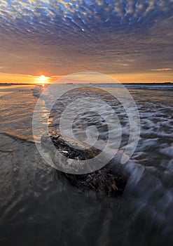 Rock and waves with dramatic sunset clouds