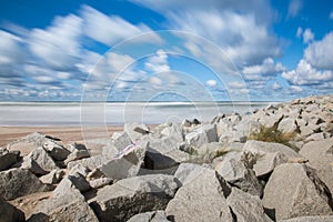 A rock on a white sand beach and blue ocean on horizon. Long exposure photography