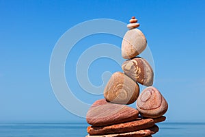 Rock zen Pyramid of balanced stones against the background of the sea and blue sky