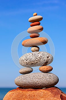Rock zen pyramid of colorful pebbles on a background of blue sky