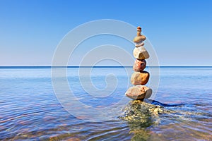 Rock zen pyramid of colorful pebbles standing in the water on the background of the sea