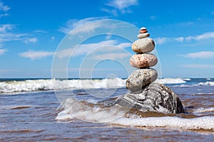 Rock zen pyramid of colorful pebbles standing in the water on the background of the sea