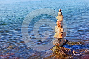 Rock zen pyramid of colorful pebbles standing in the water on the background of the sea