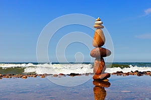 Rock zen pyramid of colorful pebbles standing in the water on the background of the sea
