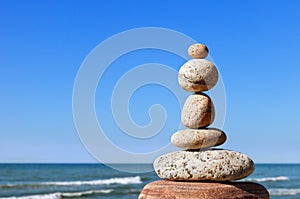 Rock zen pyramid of gray pebbles on a background of blue sky and sea