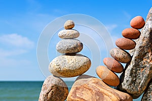 Rock zen pyramid of white and pink pebbles on a background of blue sky and sea