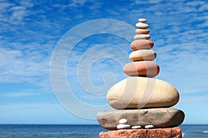 Rock zen pyramid of white and pink stones on a background of blue sky and sea