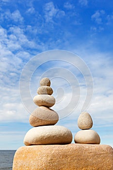 Rock zen pyramid of white stones on a background of blue sky and sea