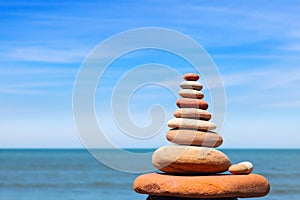 Rock zen pyramid of white stones on a background of blue sky and sea