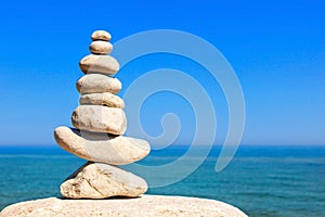 Rock zen pyramid of white stones on a background of blue sky and sea