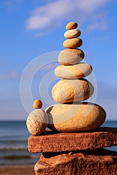 Rock zen pyramid of yellow stones on a beach on the background of the sea. Concept of Life balance