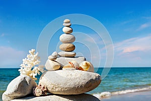 Rock zen of white stones, shells and coral on a background of the summer sea and blue sky