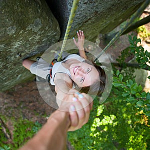 Rockclimber helping to female climber to reach top of mountain