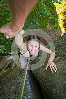 Rockclimber helping to female climber to reach top of mountain