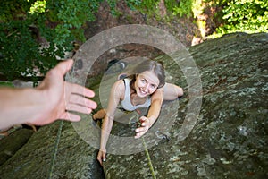 Rockclimber helping to female climber to reach top of mountain