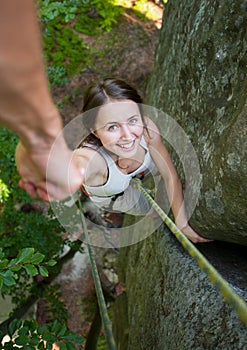 Rockclimber helping to female climber to reach top of mountain