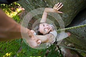 Rockclimber helping to female climber to reach top of mountain