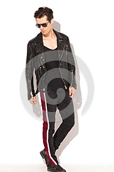 Rocker man in leather jacket and sunglasses walking