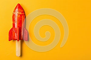 Rocket shaped summer ice lolly on a bright yellow background