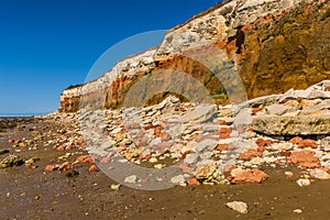 The rockfall at Old Hunstanton beach reflects the triple layers found in the white, red and orange stratified cliffs, Norfolk, UK