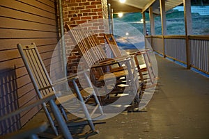 Rocking chairs on broad wooden porch under evening lights