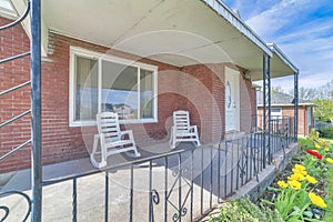 Rocking chairs on the front porch of a house with red brick wall and white door
