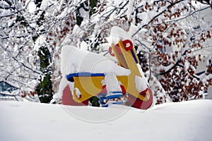 Rocking motorcycle on a spring, wooden toy in red and yellow  in garden in winter, with  snow covered .