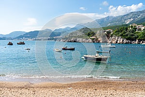 Rocks in the adriatic sea in a small coast village in Budva, Montenegro. Small boats in the beach in turquoise blue water and