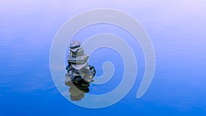 Rocks balanced on each other in blue tranquil water