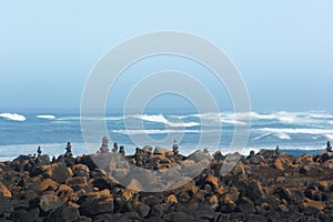 Rocks balancing in stack on a stone covered beach with ocean behind