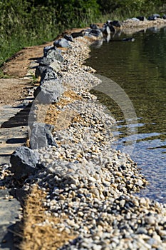 Rocks on bank of natural swimming pond or pool NSP