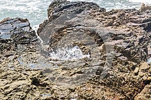 Rocks by the beach with waves splahes