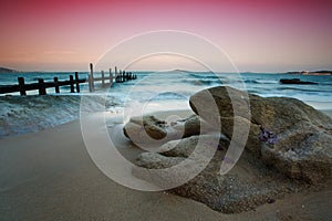 Rocks on the beach and wooden pier